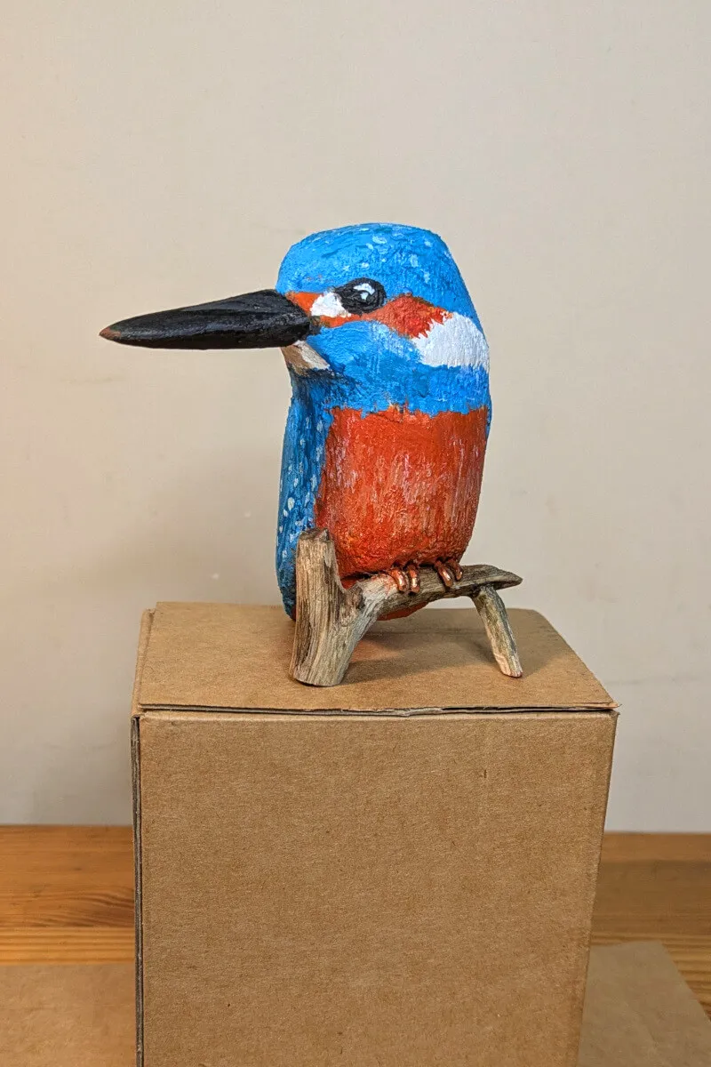 La statuette de face, l'oiseau regarde vers la gauche de l'image