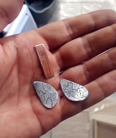 Photo de trois petites plaques (une de cuivre, deux de zinc) avec des motifs gravés à l'acide